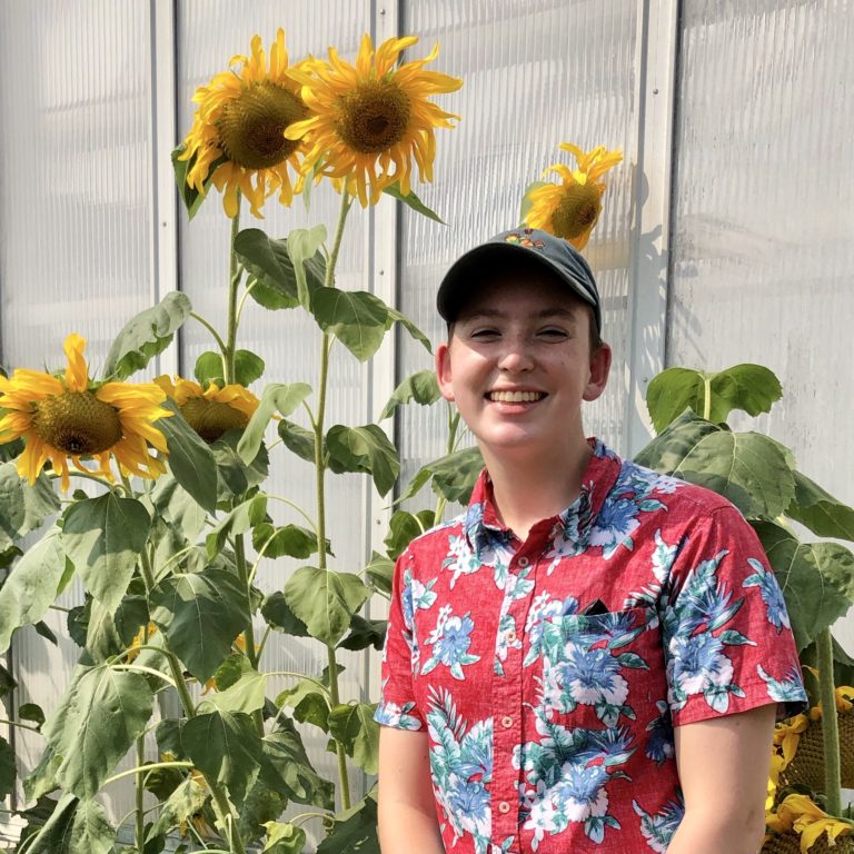 Photo of Alison Benbow (me) next to a sunflower