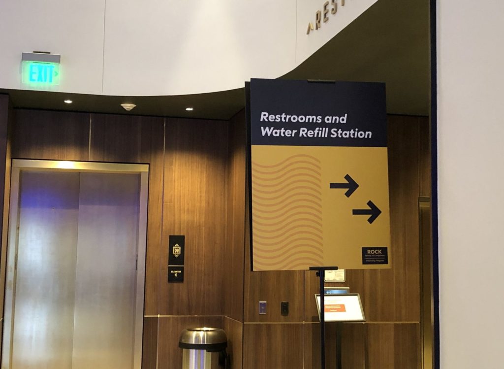 photo of a wayfinding sign that reads, "restrooms and water refill station"
