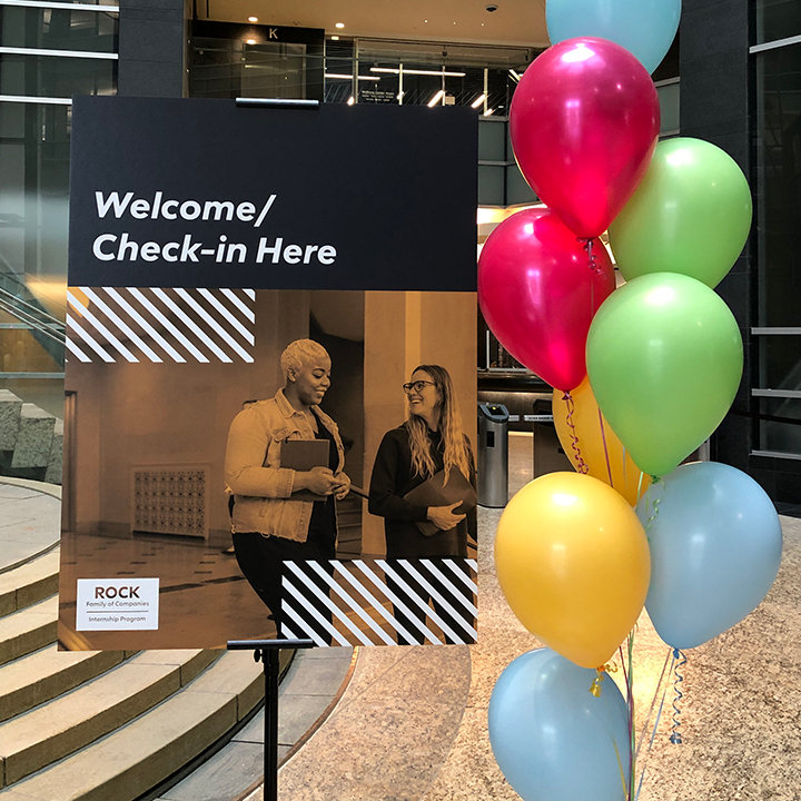 photo of balloons next to a sign that reads "welcome / check-in here"