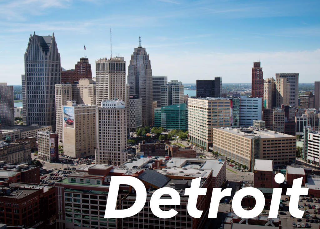 image of the front of a postcard featuring an image of downtown buildings in Detroit and the text "Detroit"