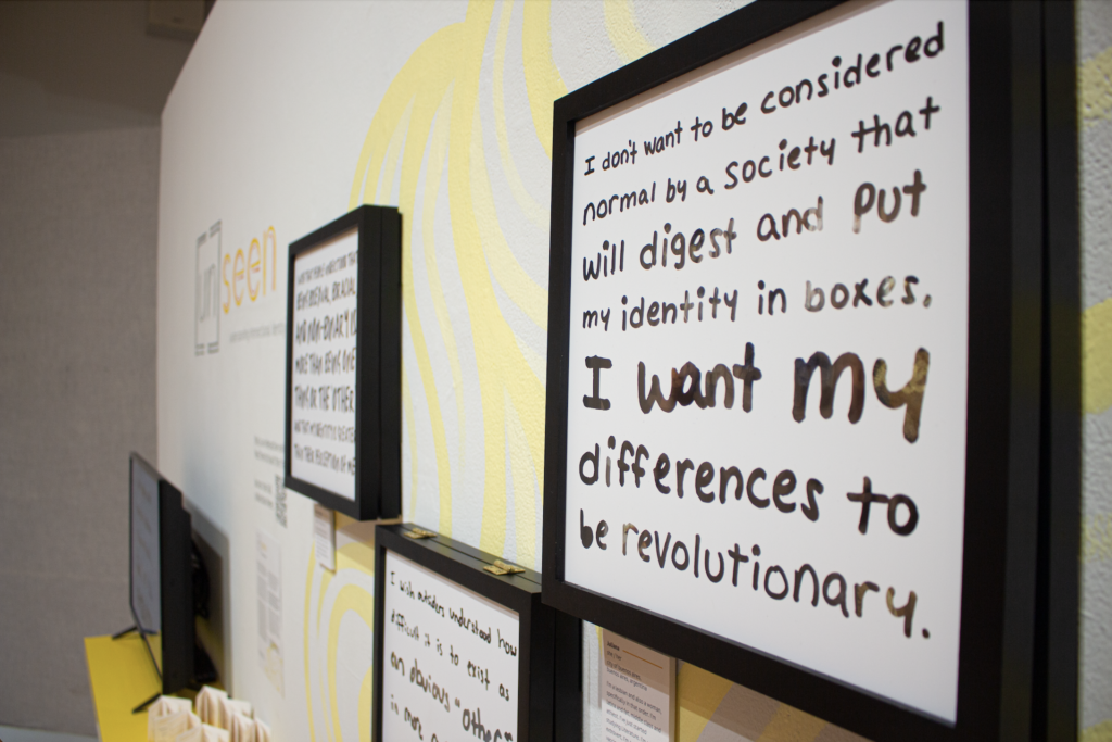 Photo of a frame hanging on a wall. Text on the frame reads, "I don't want to be considered normal by a society that will digest and put my identity in boxes. I want my differences to be revolutionary"