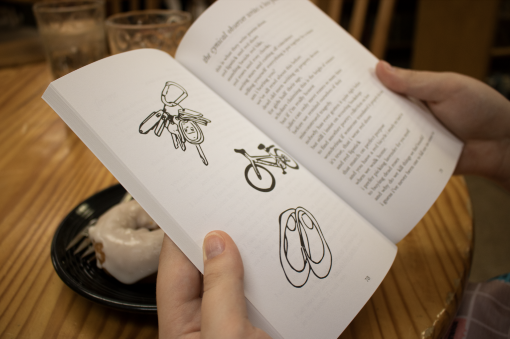 photo of hand holding eighteen, which is opened to a drawing of a bike, keys, and flats