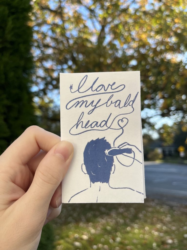 Photos of an 8 page zine held up against a blurry outdoor background. Drawings are in dark blue on a white background. Panel 1: Drawing of a person with light skin and dark hair from behind as they use clippers to shave their head. The cord from the clippers forms the words “I love my bald head” in script at the top of the panel.